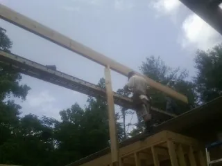 Carpenter setting a ridge beam over a new addition frame — Ice Dam Removal by Roofing Brothers in Cedar Lane