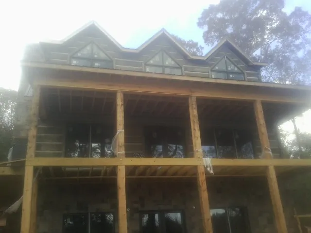 Dormers and porch framing on a large log home under construction — Roof Coating work by our crew in Cedar Lane