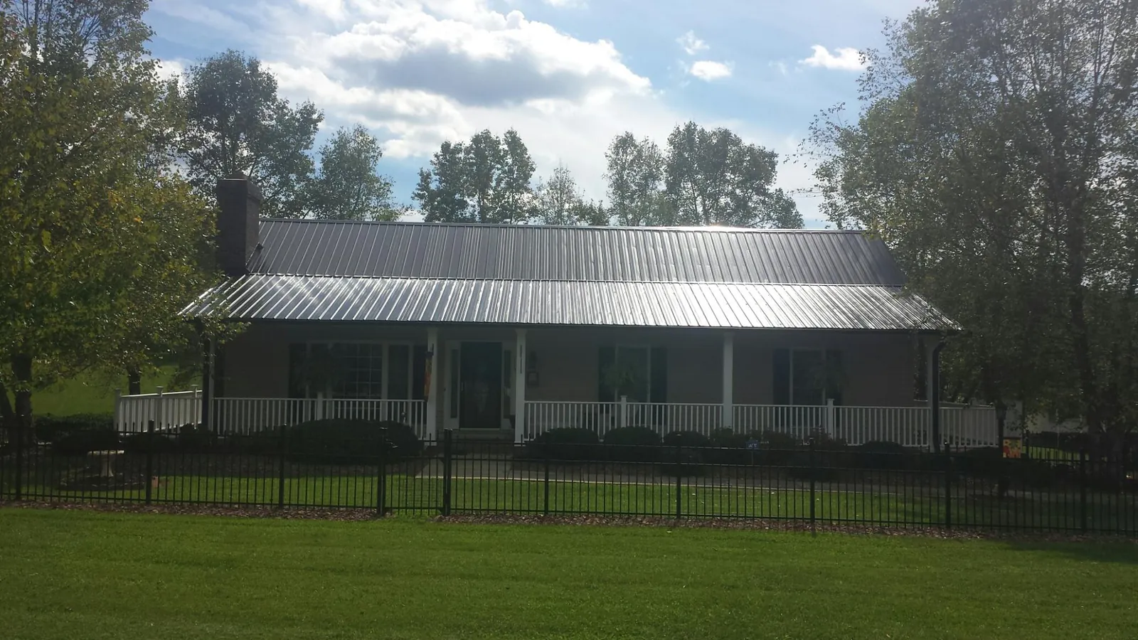Gray metal roof on a brick ranch with a full width front porch — Gutter Guard Installation work by our crew in Cedar Lane