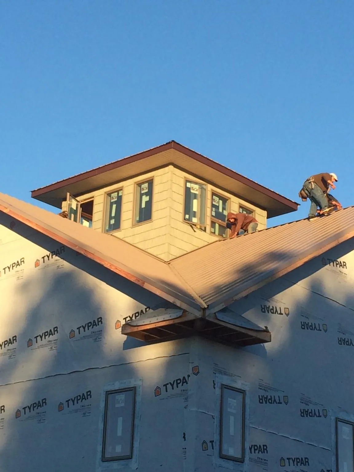 Roofers working around a rooftop cupola on a new metal roof at sunset — Roof Waterproofing in Cedar Lane by Roofing Brothers